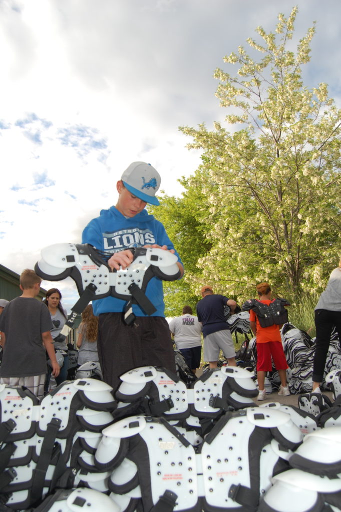 Collin Sheffield stacks football shoulder pads by size as part of the equipment and inventory split. Photo: Cavett Ishihara
